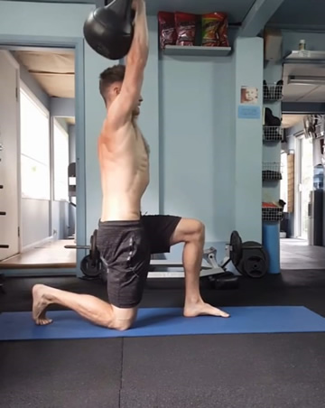 Personal Trainer Oliver Ody demonstrating a Half-kneeling shoulder press with kettlebell